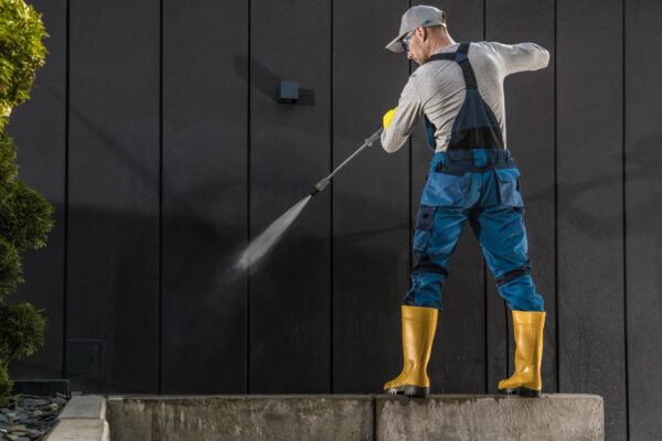 worker washing exterior of house