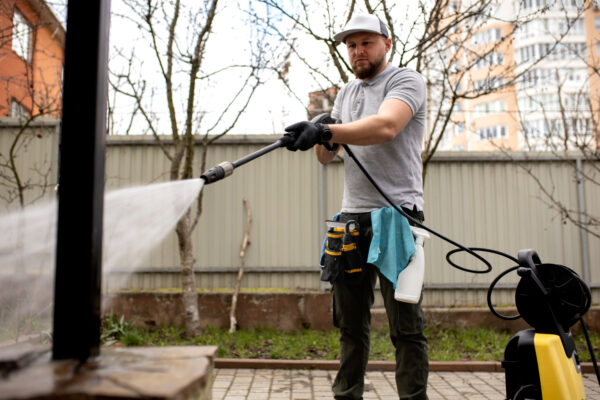 worker washing exterior of house